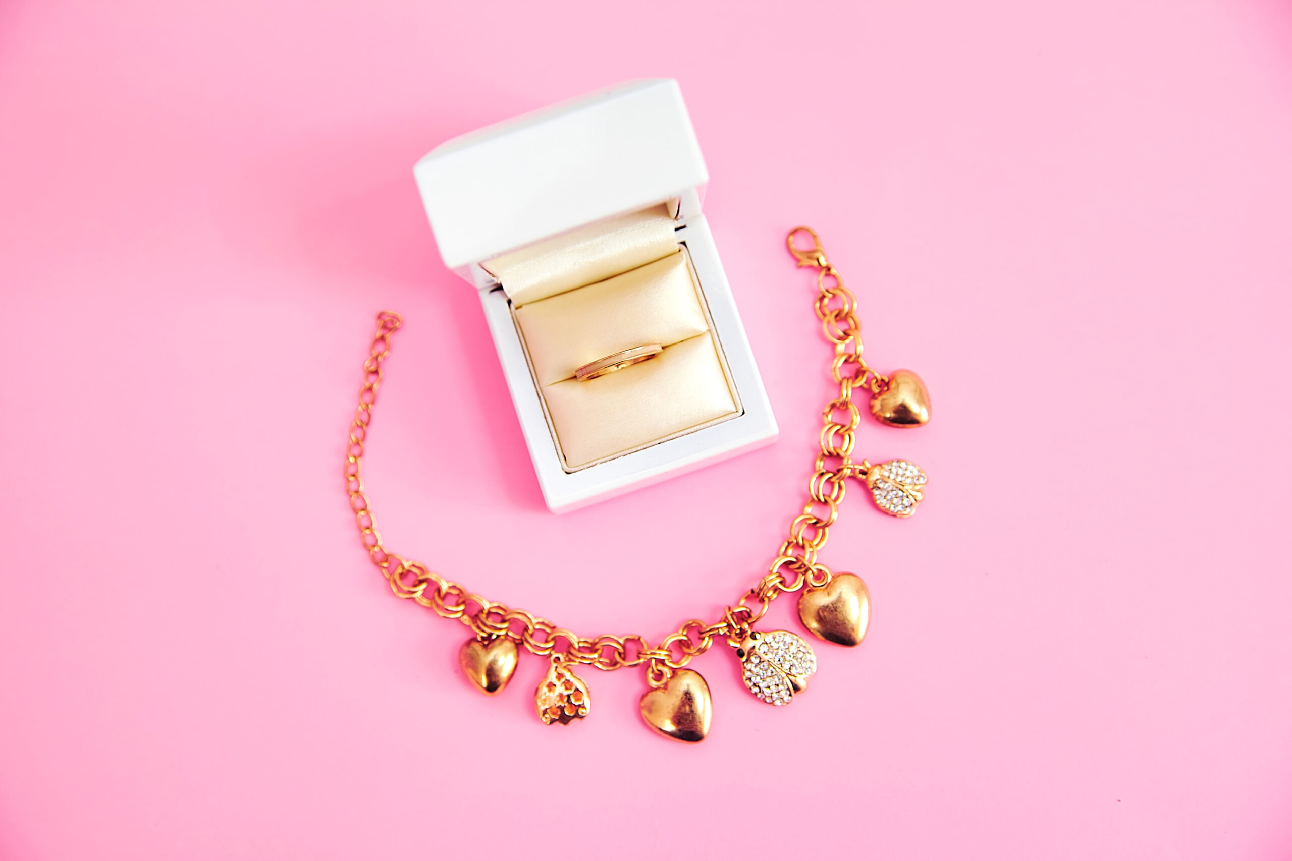 Pulsera y anillo sobre fondo rosa